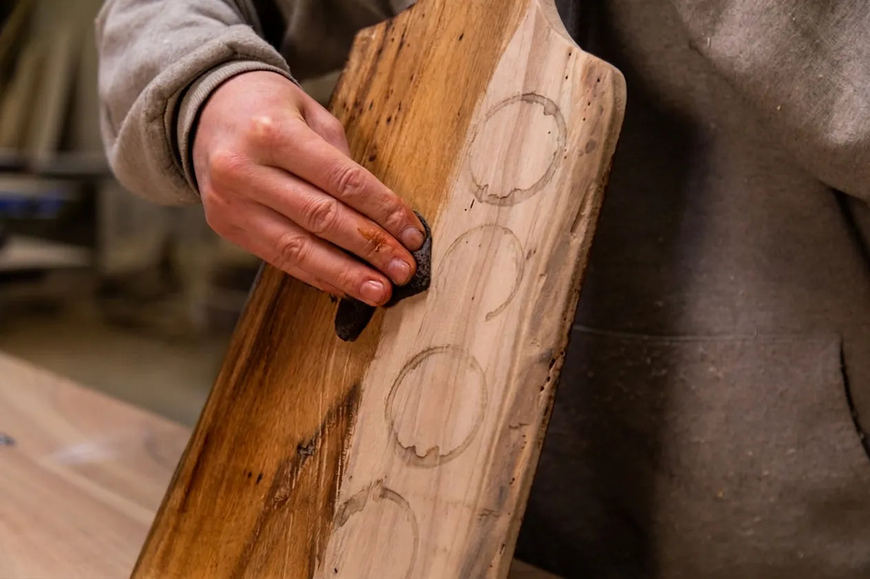 Teakhouten snijplank met kringen van glazen die wordt schoon gemaakt met een doekje