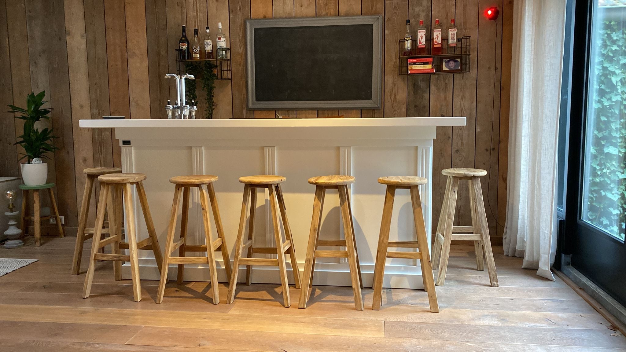 Teakhouten barkrukken geplaatst aan en witte bar