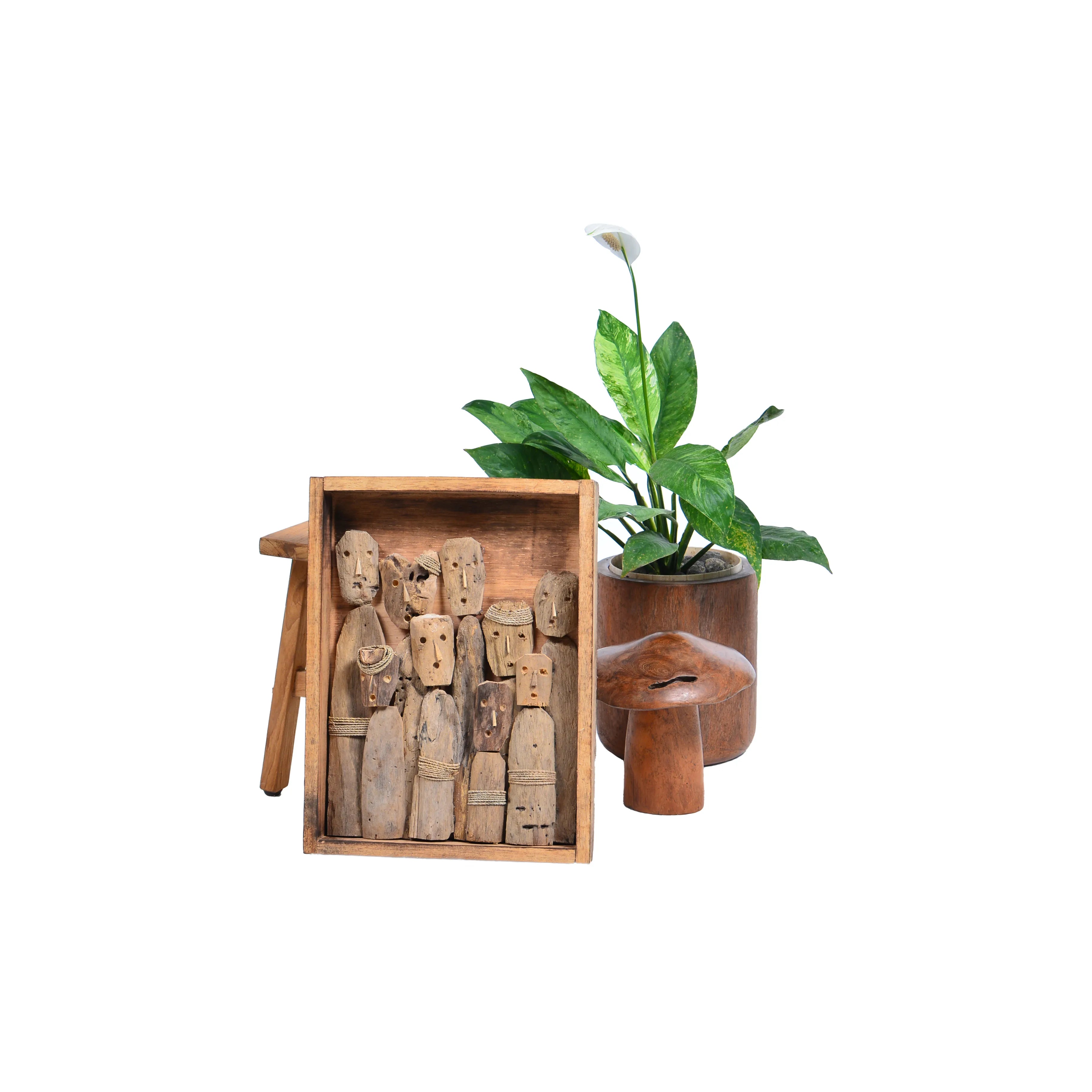 Teakhouten wanddecoratie met figuren naast plant en woonaccessoires.