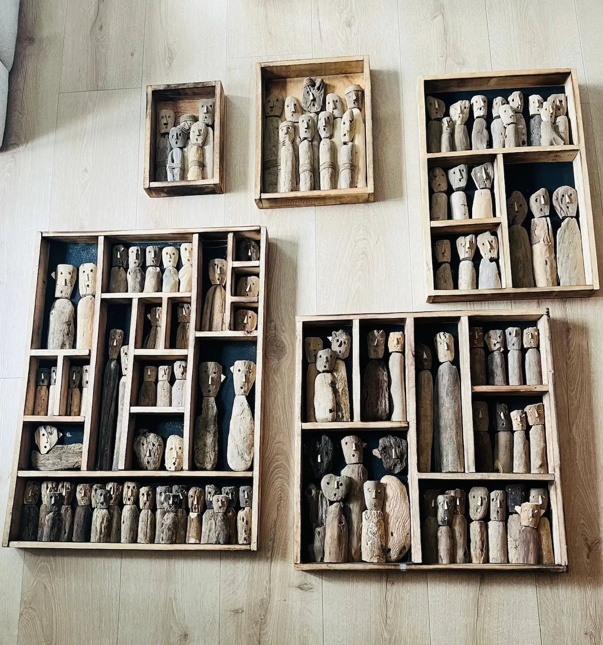 Meerdere houten wanddecoraties met figuren van gerecycled hout aan muur.