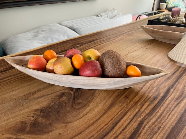 Zijkant van de houten fruitschaal Prauw gevuld met fruit en geplaatst in een woonkamer