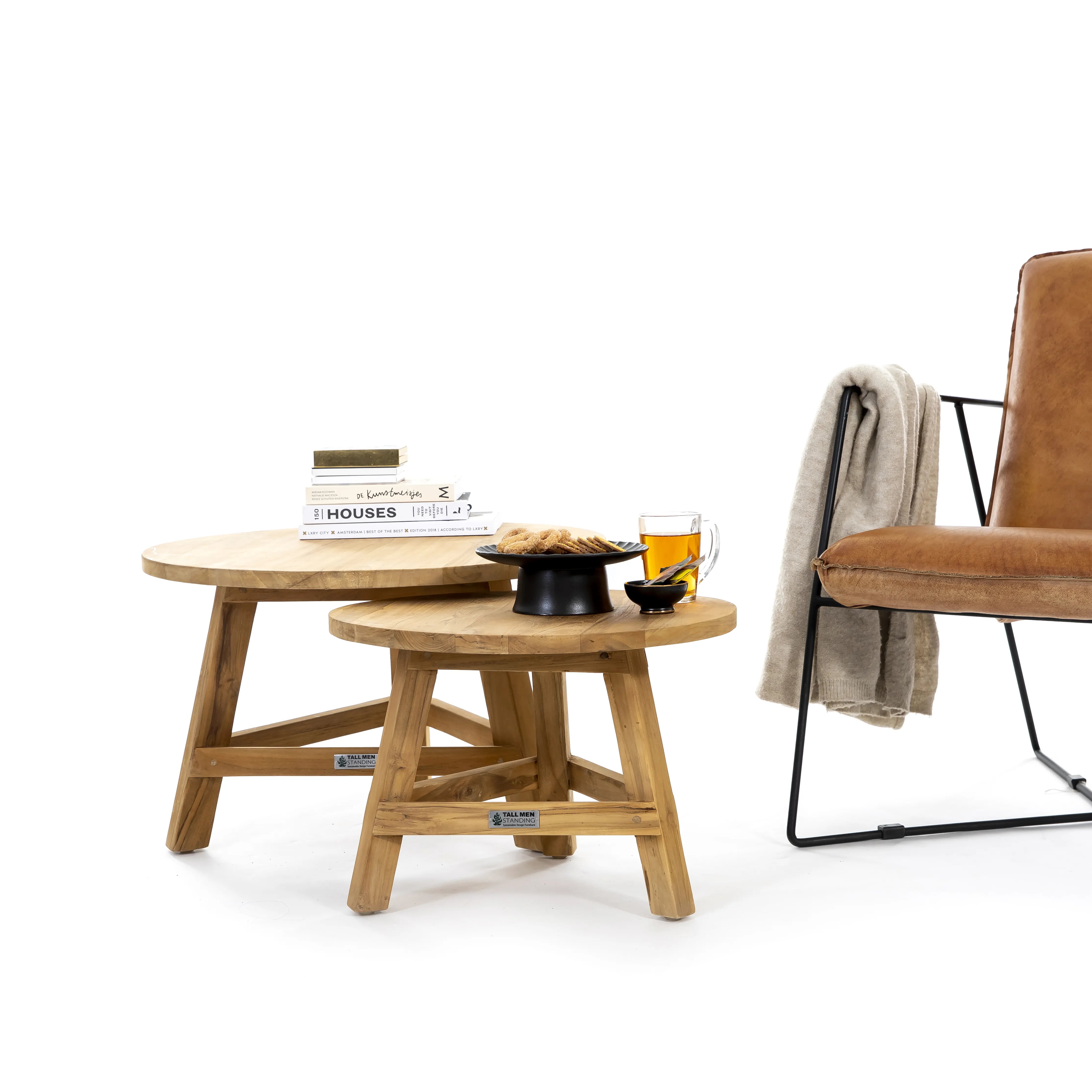 Set van een hoge en lage salontafel gemaakt van teakhout met daarop boeken,  thee en koekjes en naast de salontafels een stoel