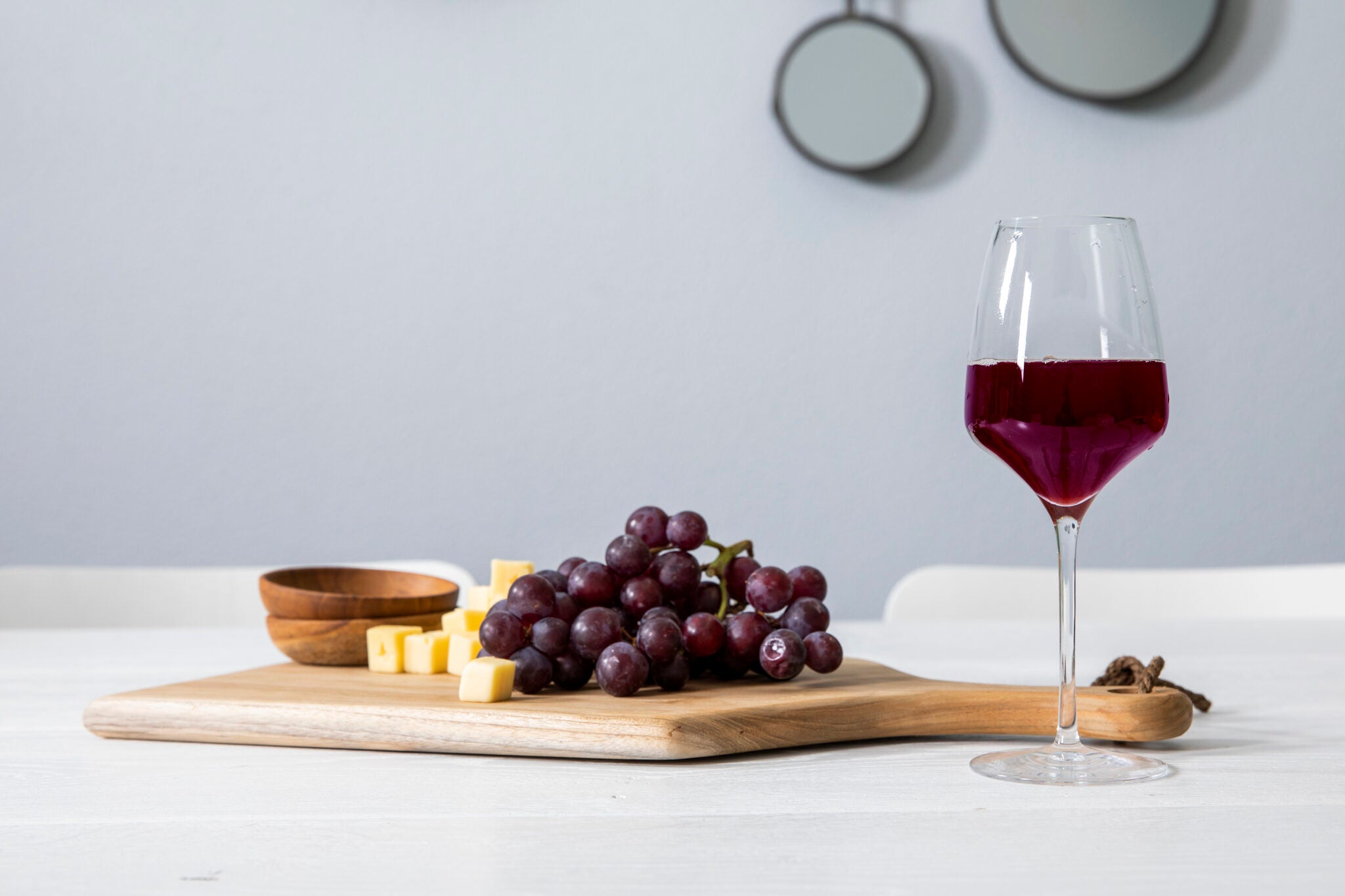 Teakhouten tapasplank met druiven en glas wijn.